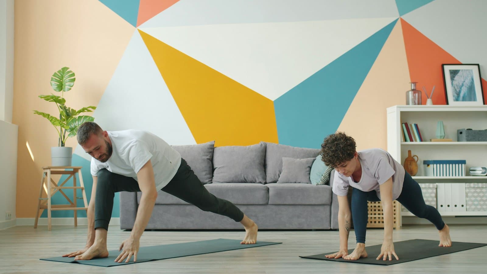 Two people follow a live class in their living room, each on their mat